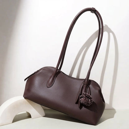 Borsa pochette minimalista curva in vera pelle morbida con ciondolo giocoso