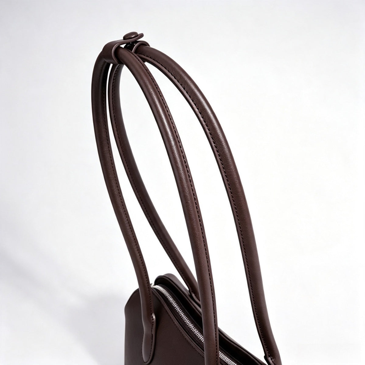 Borsa pochette minimalista curva in vera pelle morbida con ciondolo giocoso
