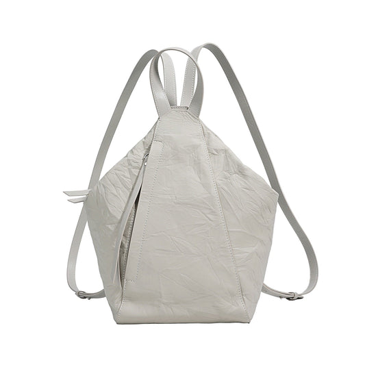 A creamy white, pleated genuine leather backpack with adjustable straps and a zipper closure, displayed against a neutral background.