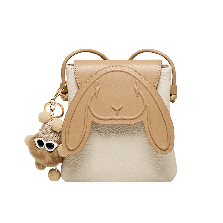 A leather mini crossbody phone bag with a whimsical rabbit design, featuring ears protruding from the top and a charm resembling a rabbit face attached to the strap.