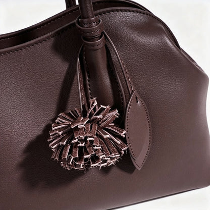 Borsa pochette minimalista curva in vera pelle morbida con ciondolo giocoso