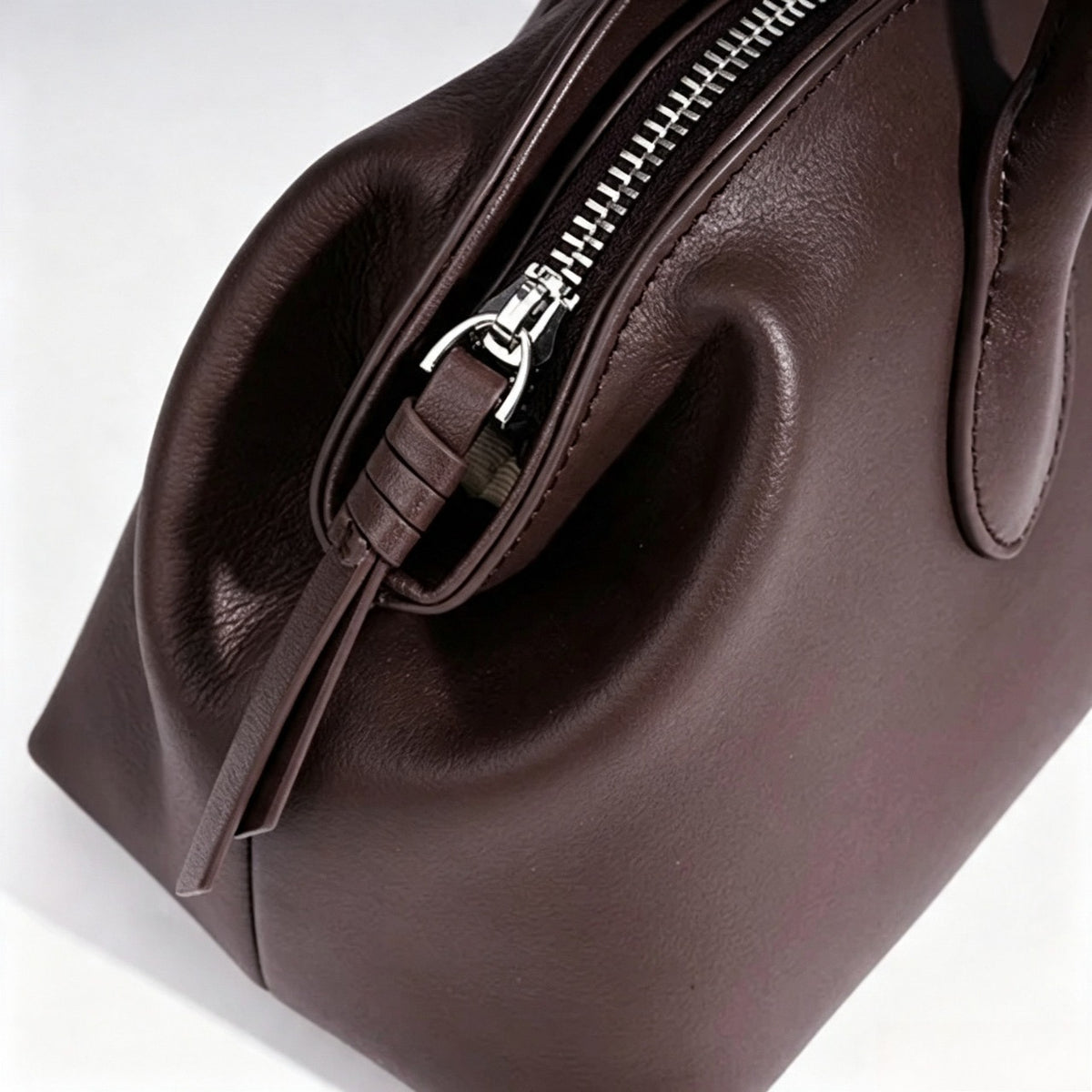 Borsa pochette minimalista curva in vera pelle morbida con ciondolo giocoso