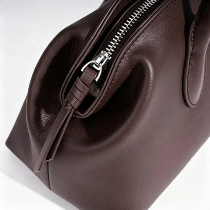 Borsa pochette minimalista curva in vera pelle morbida con ciondolo giocoso
