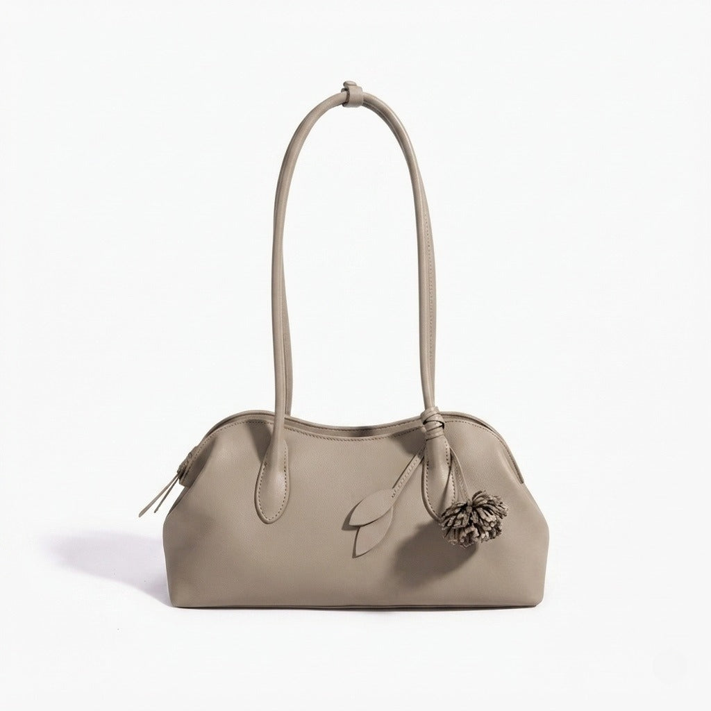 Borsa pochette minimalista curva in vera pelle morbida con ciondolo giocoso