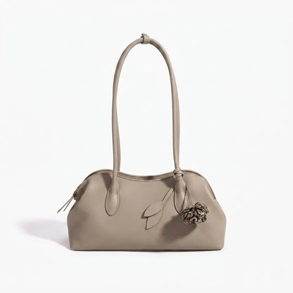 Borsa pochette minimalista curva in vera pelle morbida con ciondolo giocoso